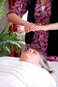Hands held over relaxed client at the close of an energy healing session