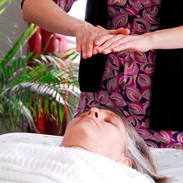 Hands held over relaxed client at the close of an energy healing session